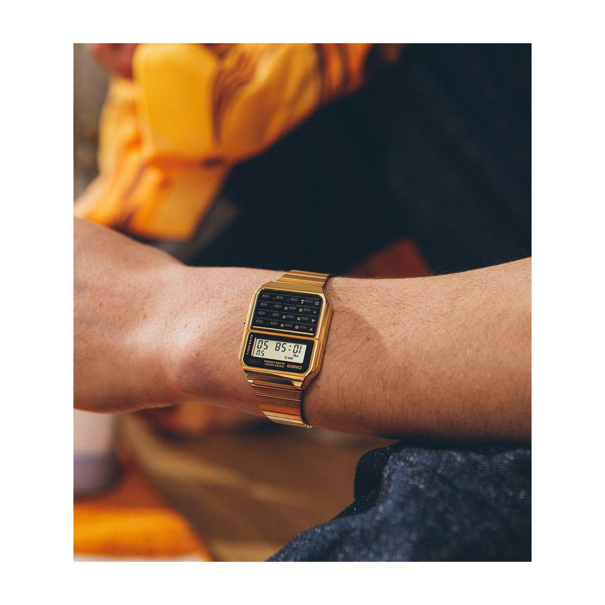 Gold-tone steel digital wrist watch on wrist, black LCD display visible