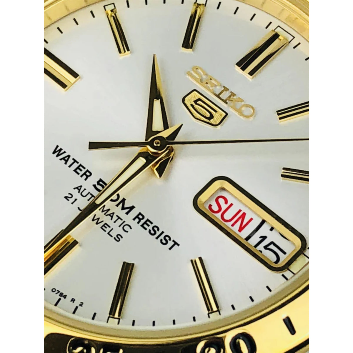 White dial detail with gold hands, SEIKO 5 badge, and SUN 15 day-date window