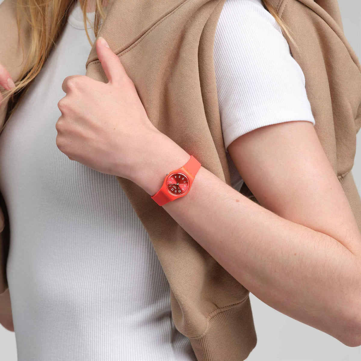 Coral red silicone strap quartz watch on wrist with round red dial and hour markers