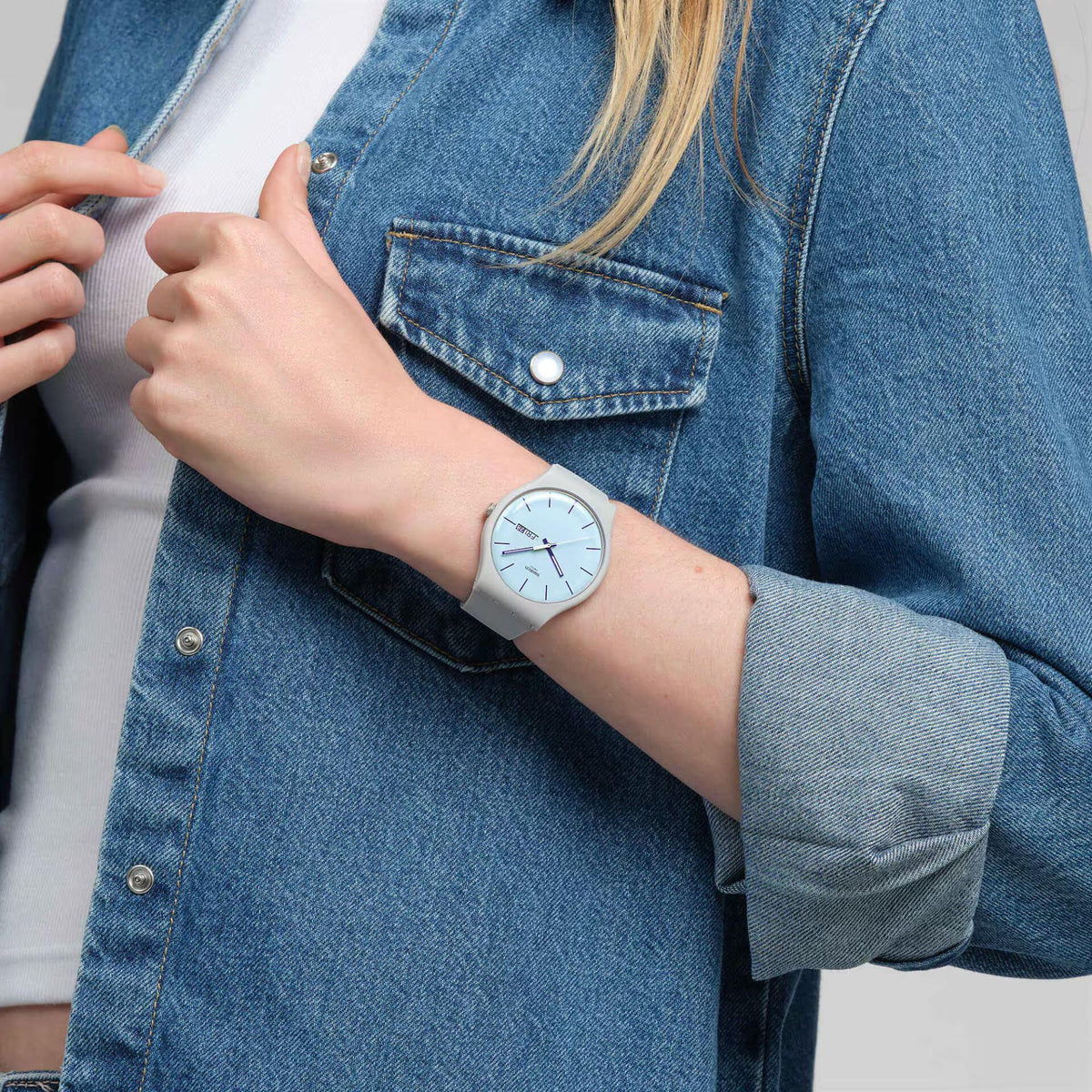 Blue dial quartz watch on wrist with gray silicone strap, analog dial and date marker