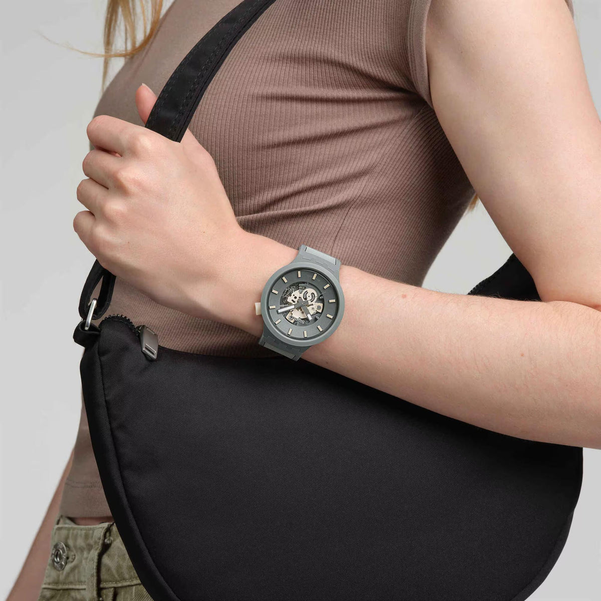 Swatch quartz watch on wrist with gray silicone strap and blue-gray skeleton dial