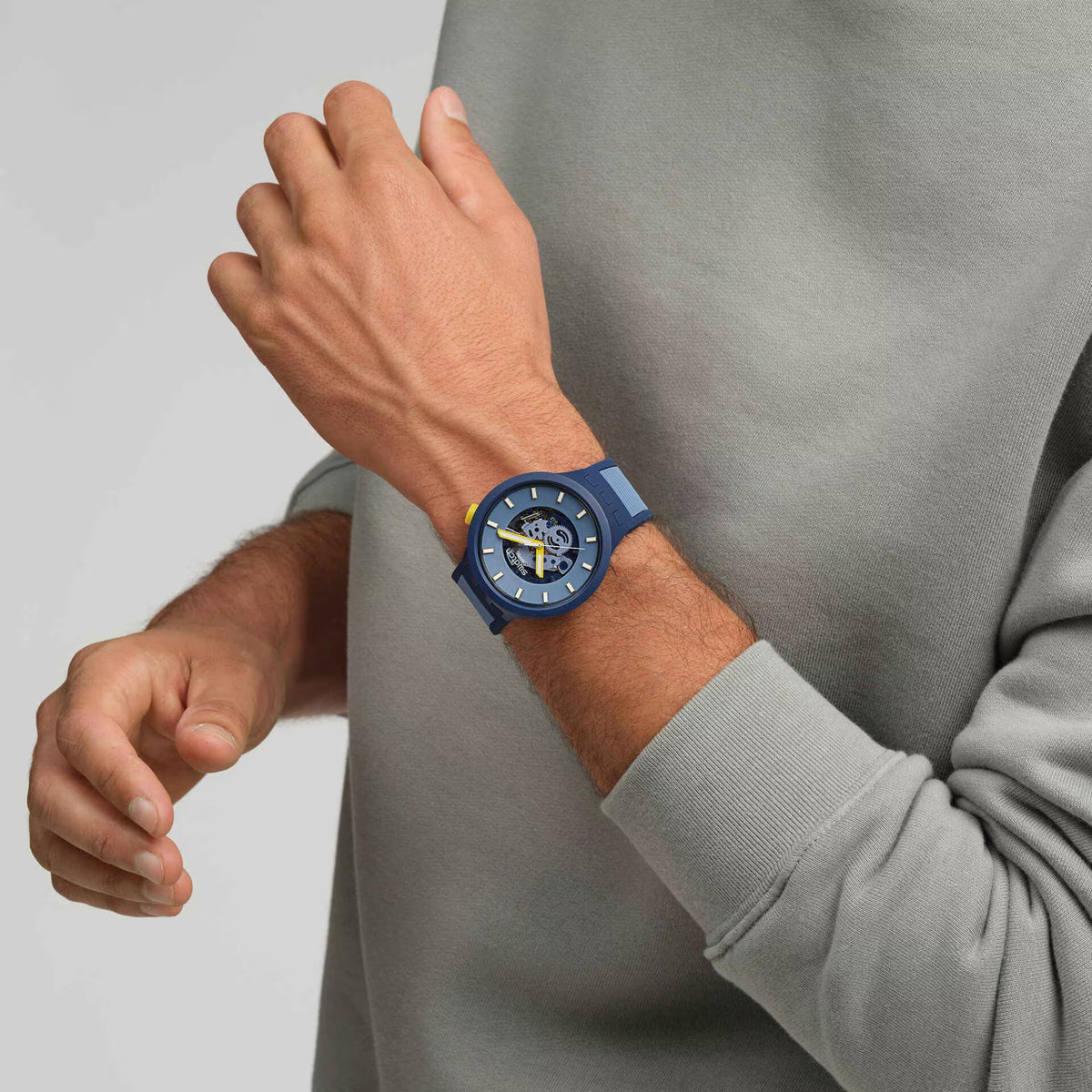 Dark blue silicone strap watch on wrist, light blue dial with yellow-accent hands