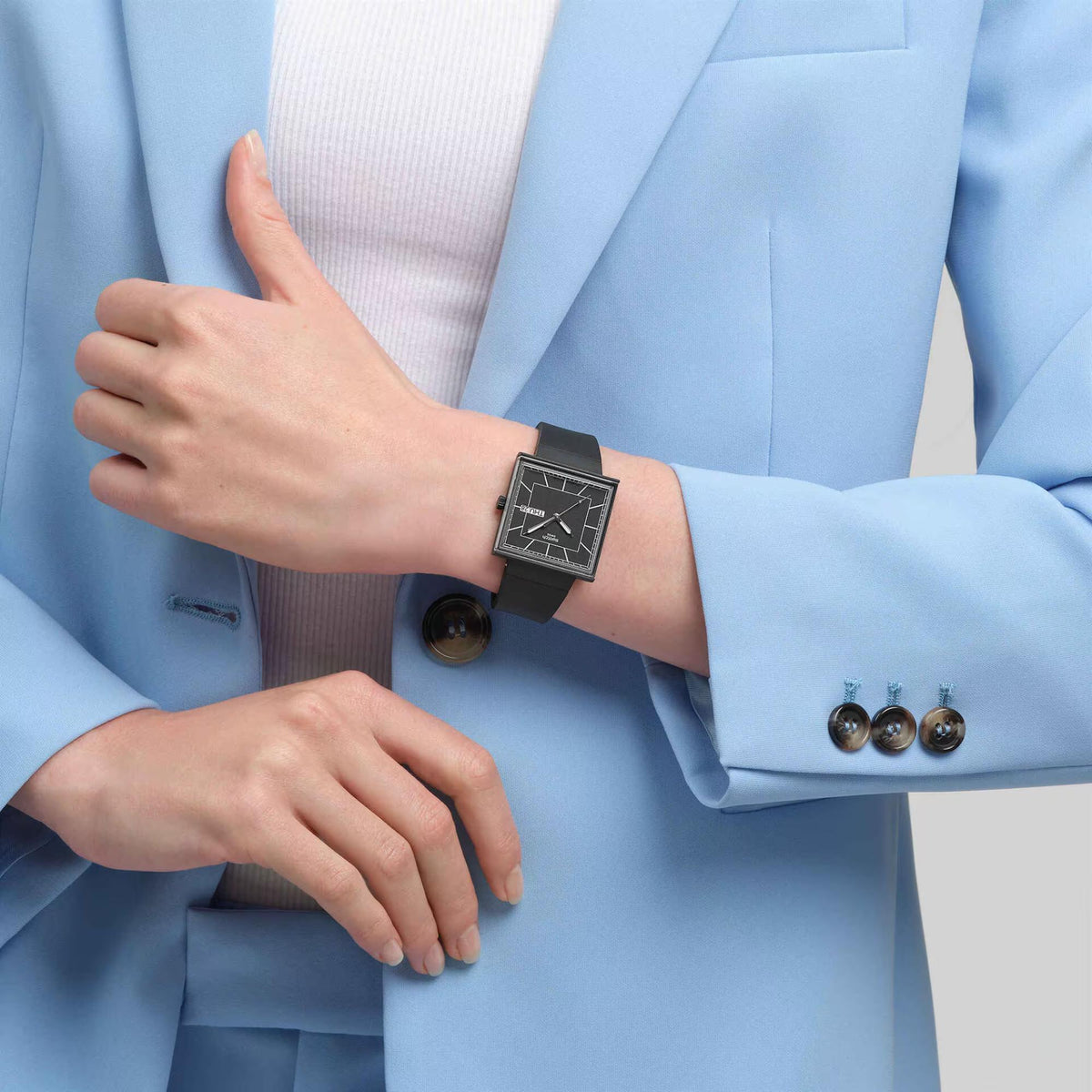 Black square quartz watch on wrist, black dial with white markers and black silicone strap