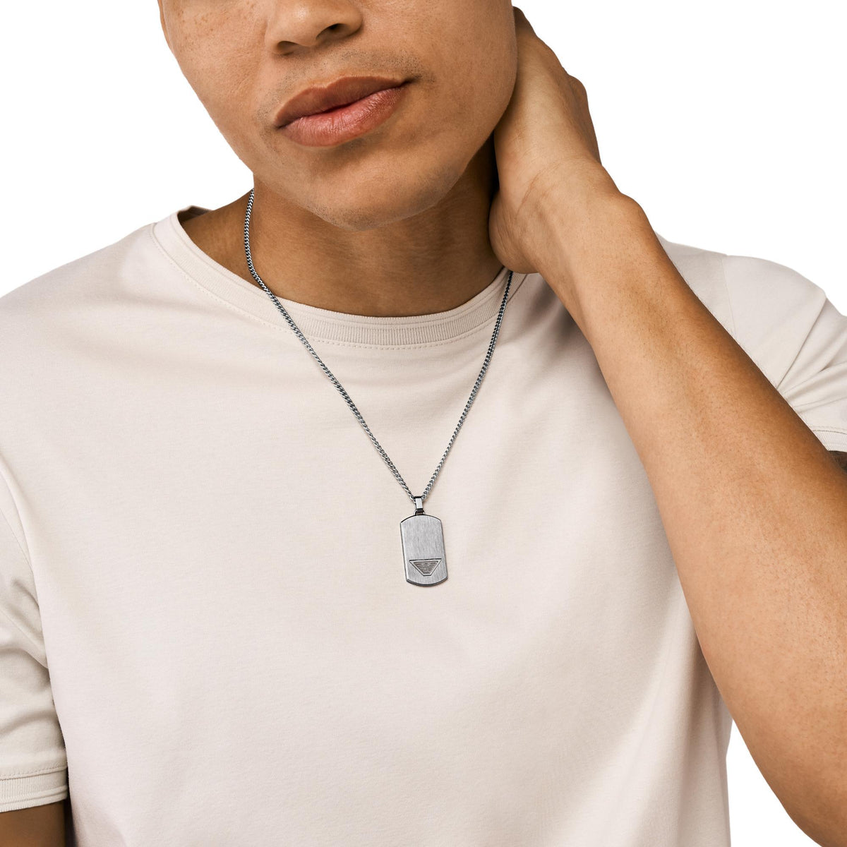 Stainless steel dog tag necklace worn on a chain over a light T-shirt