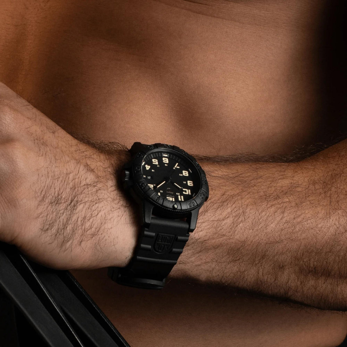 Black rubber quartz watch worn on wrist, black dial with gold-tone indices