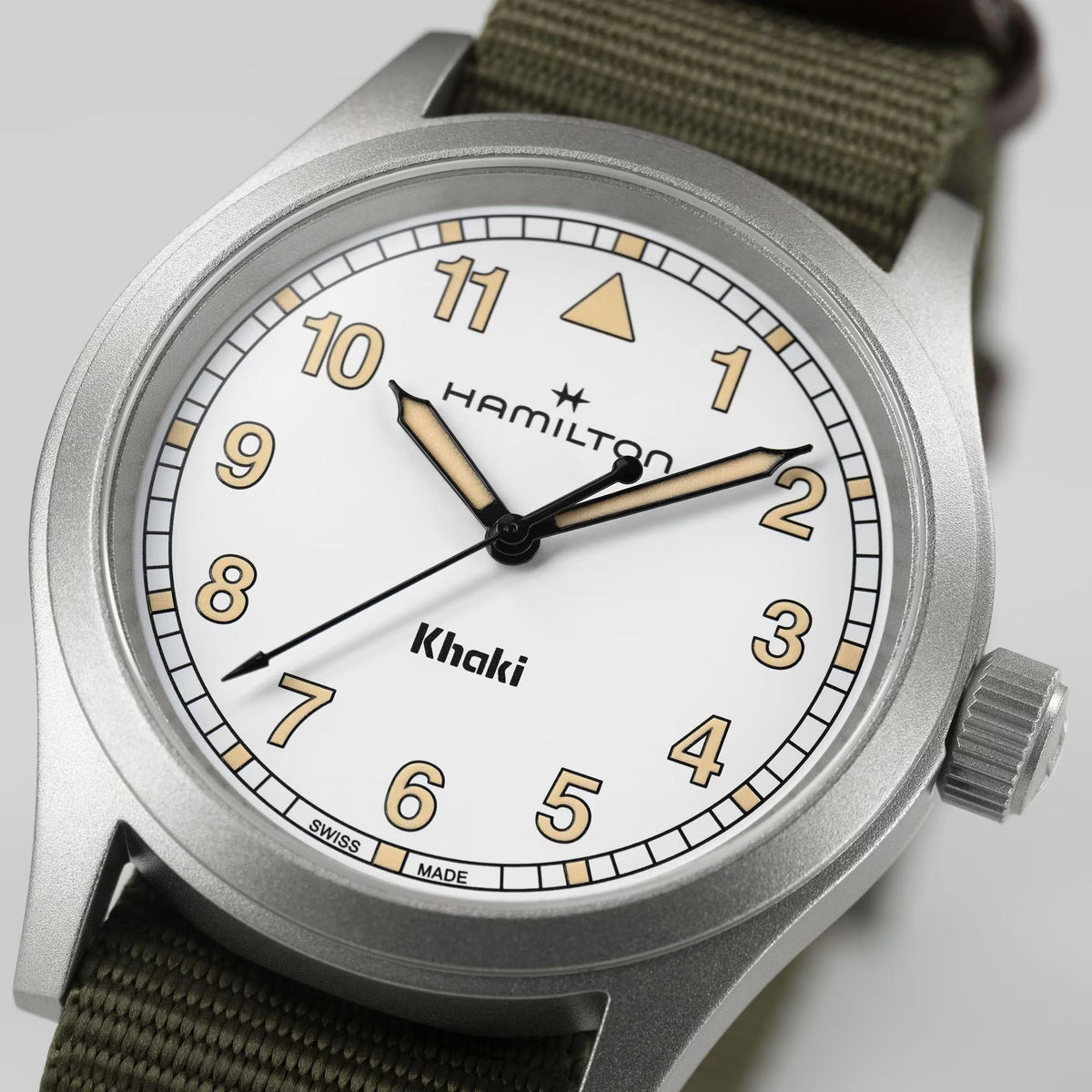 Hamilton Khaki Field H69401910 mens watch resting flat showing white dial, sandblasted steel case, and olive green NATO strap