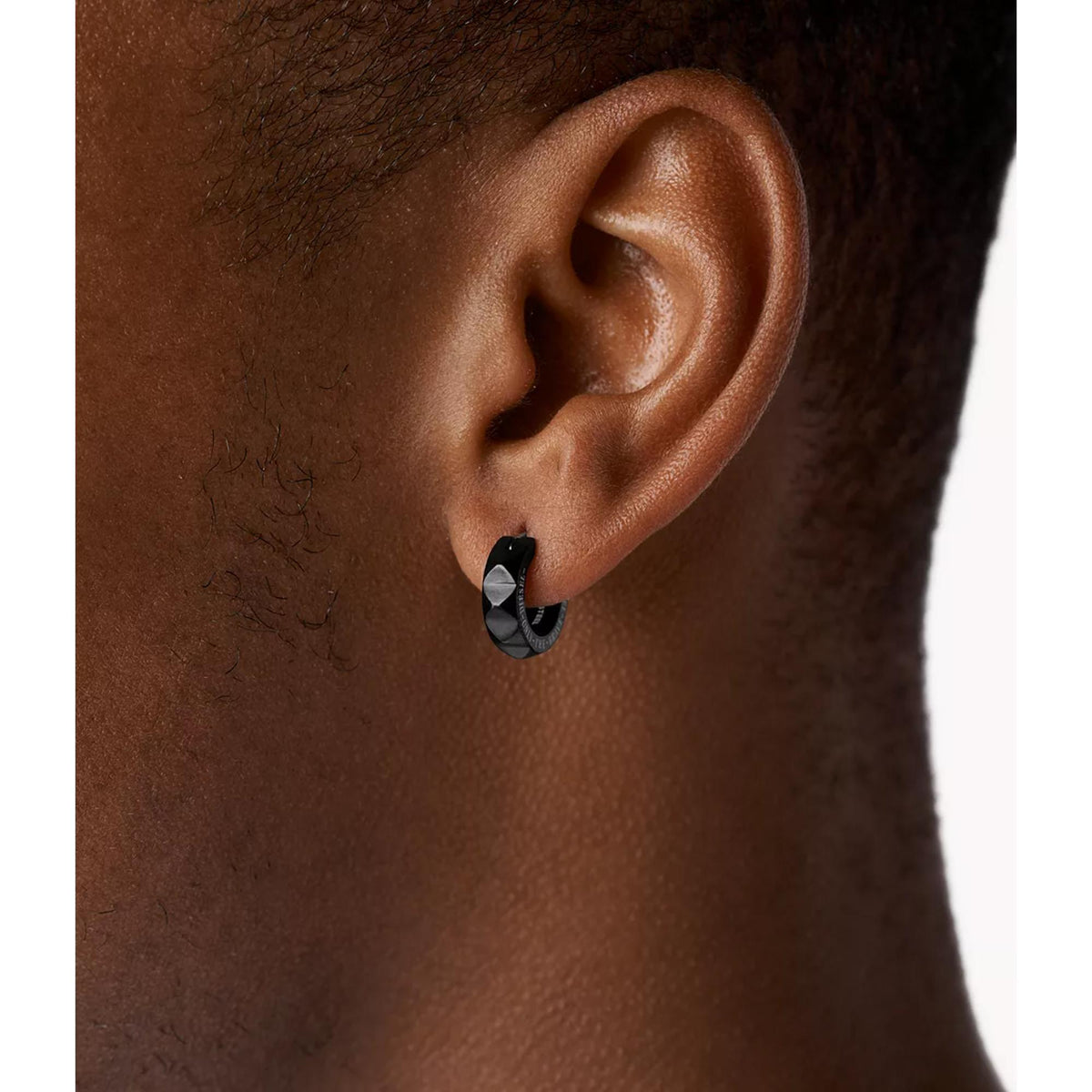 Diesel black studded huggie earring on ear, black hoop with dark geometric texture