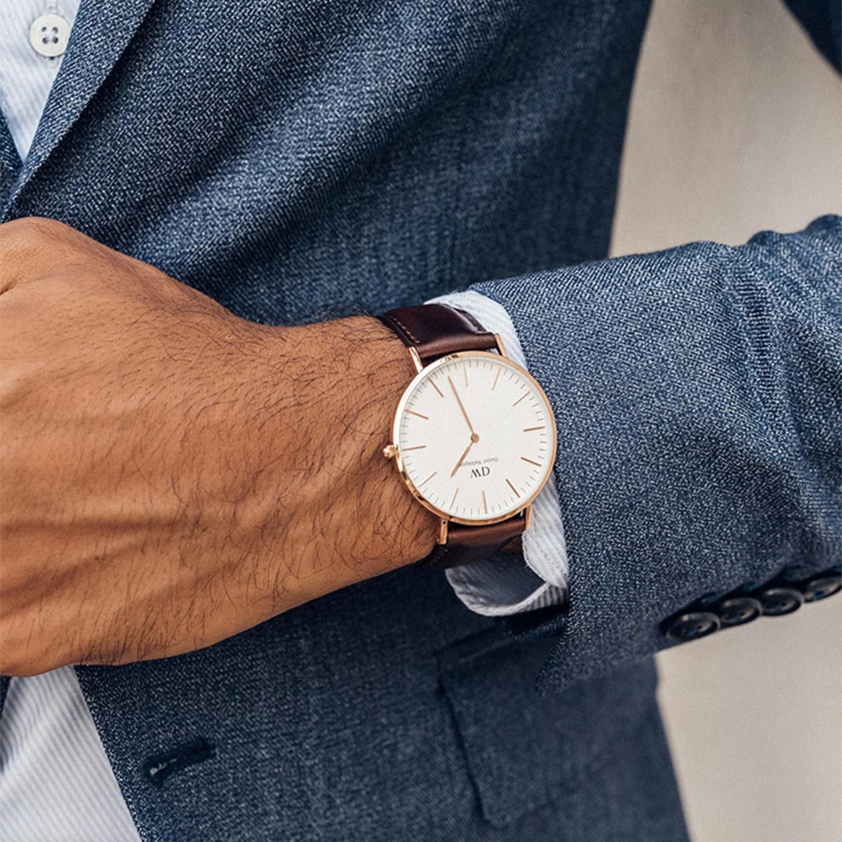 Men's quartz watch on wrist with white dial, brown leather strap, and rose-gold case.
