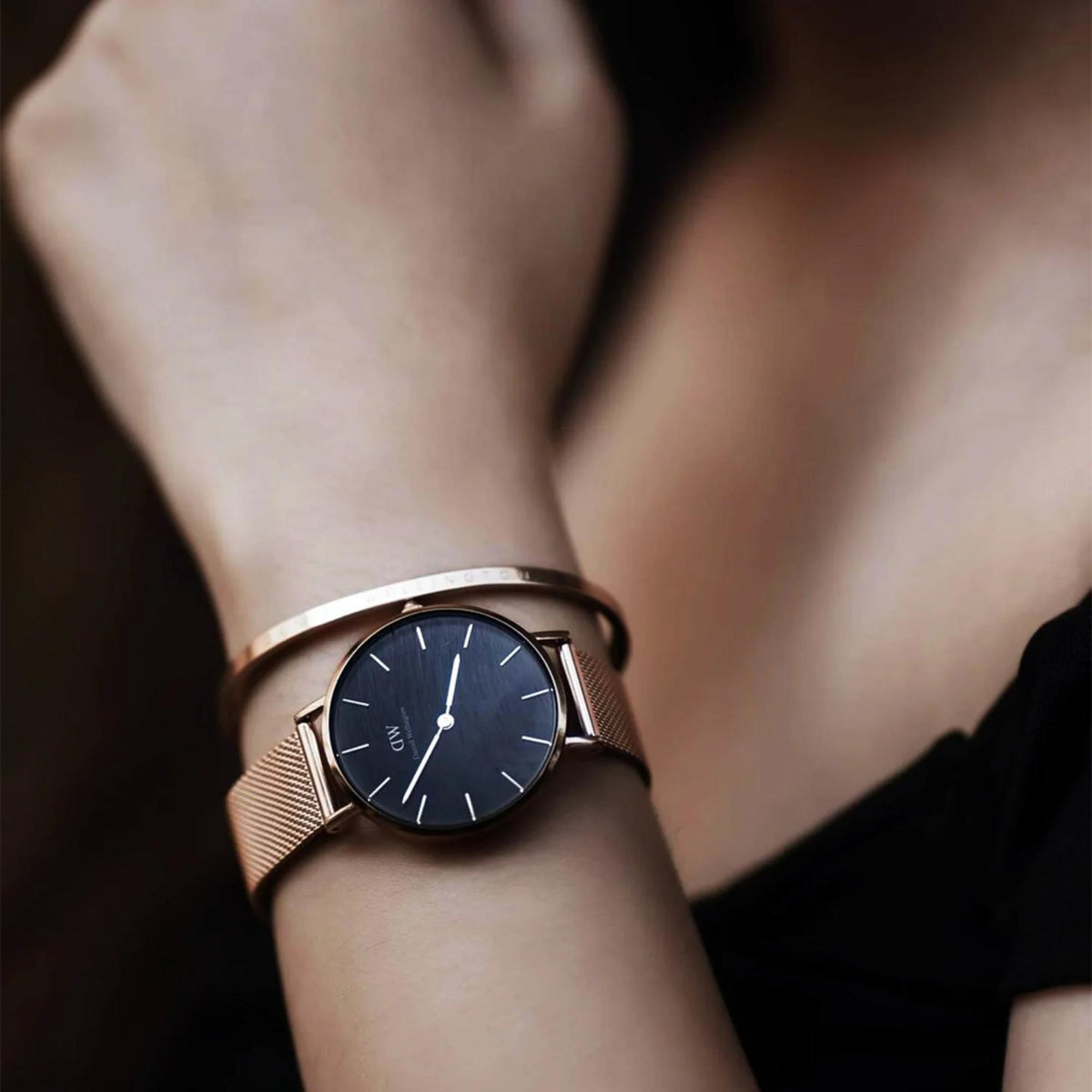 Rose-gold mesh strap analog watch with dark blue-black dial on wrist