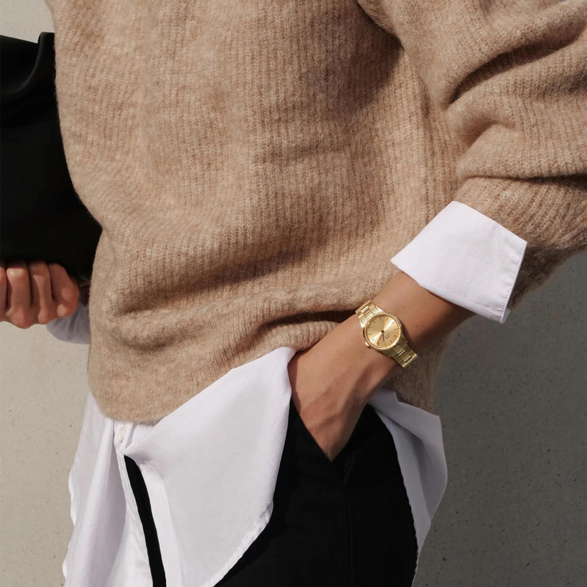 Gold-tone steel watch on wrist with round beige dial and metal bracelet