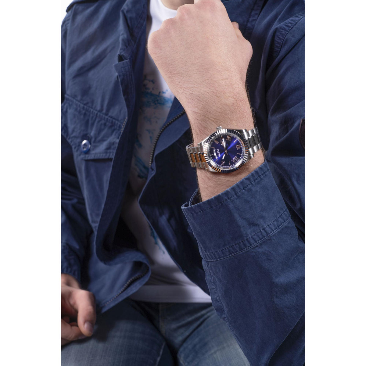 Men's blue-dial stainless steel watch worn on wrist with metal link bracelet