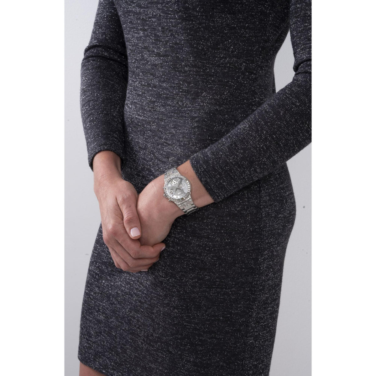 Silver stainless steel watch worn on wrist with dark textured sleeve
