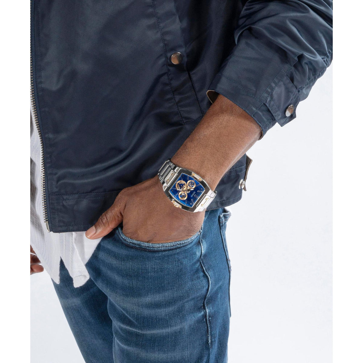 Men’s wristwatch with blue dial and silver link bracelet on a man’s arm in a dark jacket.