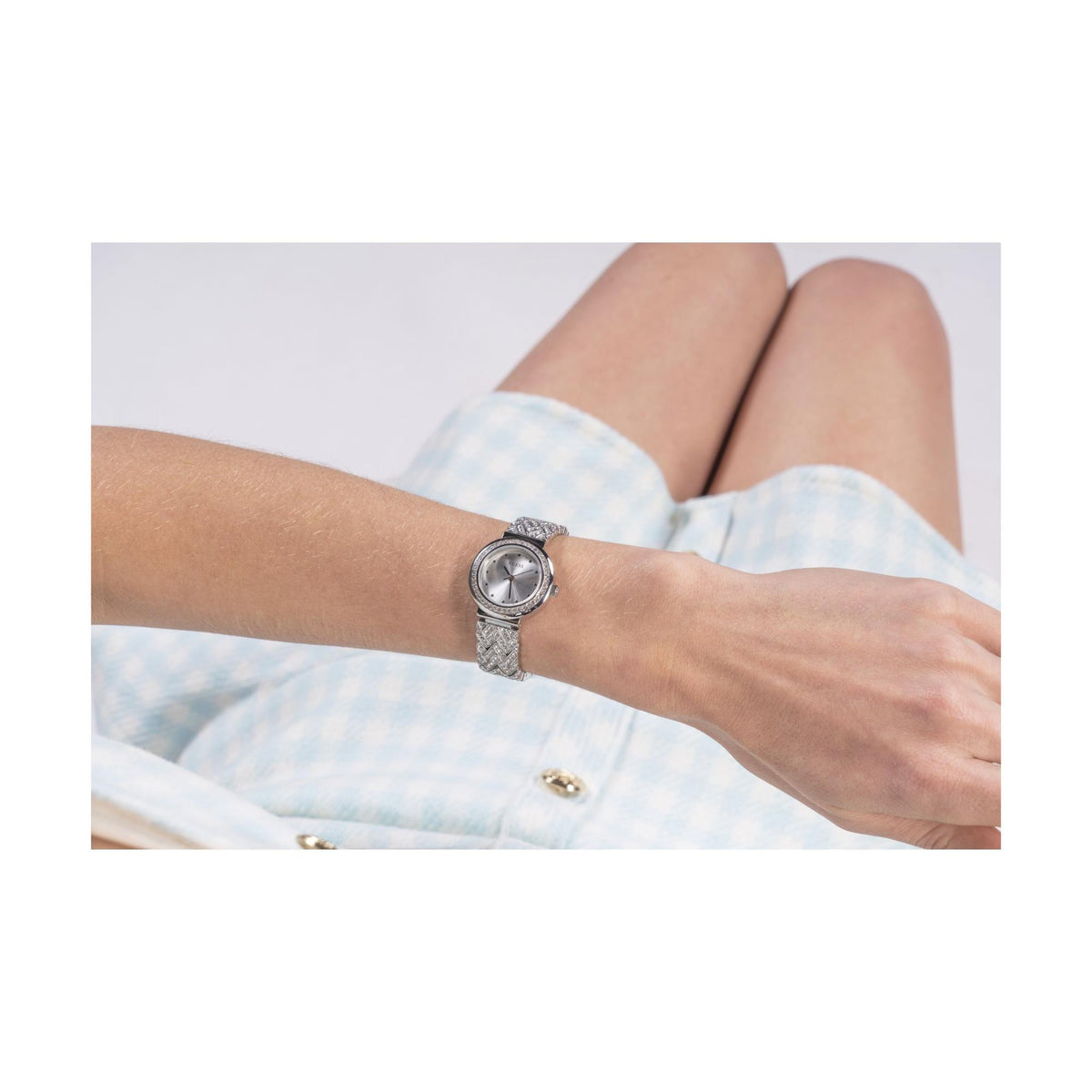Silver analog watch on wrist with round dial and sparkly textured bangle bracelet