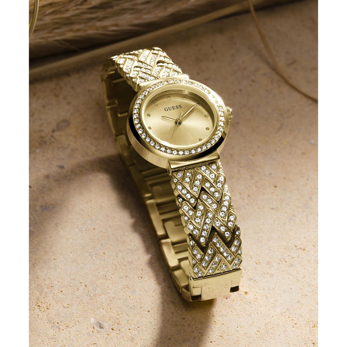 Gold-tone analog watch with champagne dial and rhinestone strap, angled wristwatch view