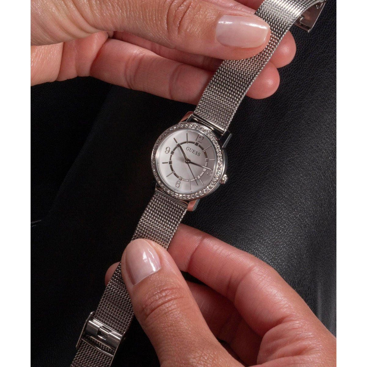 GUESS analog watch on silver mesh band with white dial and crystal bezel on wrist