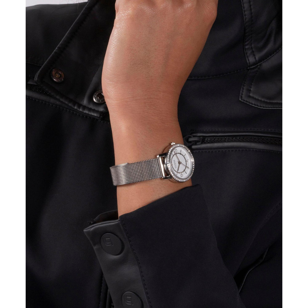 Women's analog watch on silver mesh band, white dial, crown detail at side