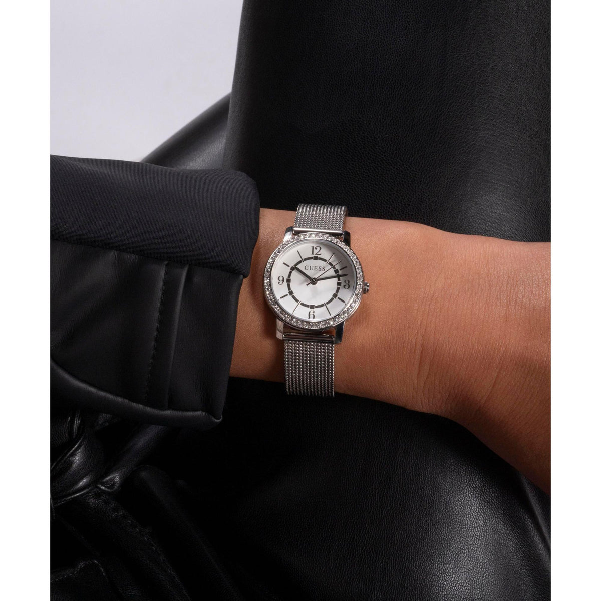 Women's analog watch with silver mesh band and white dial, crystal bezel on wrist
