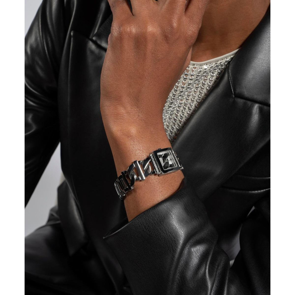Silver rectangular ladies watch on wrist with black-and-silver faceted links and steel bracelet