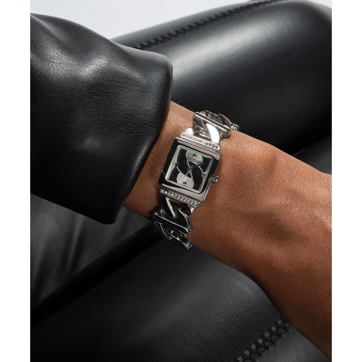 Silver rectangular ladies wristwatch with rhinestone bezel and polished steel bracelet on arm