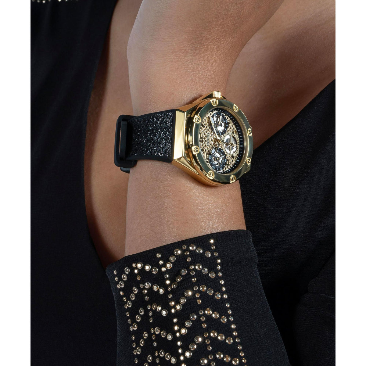 Gold-tone ladies watch on wrist with black textured silicone strap, detailed dial view