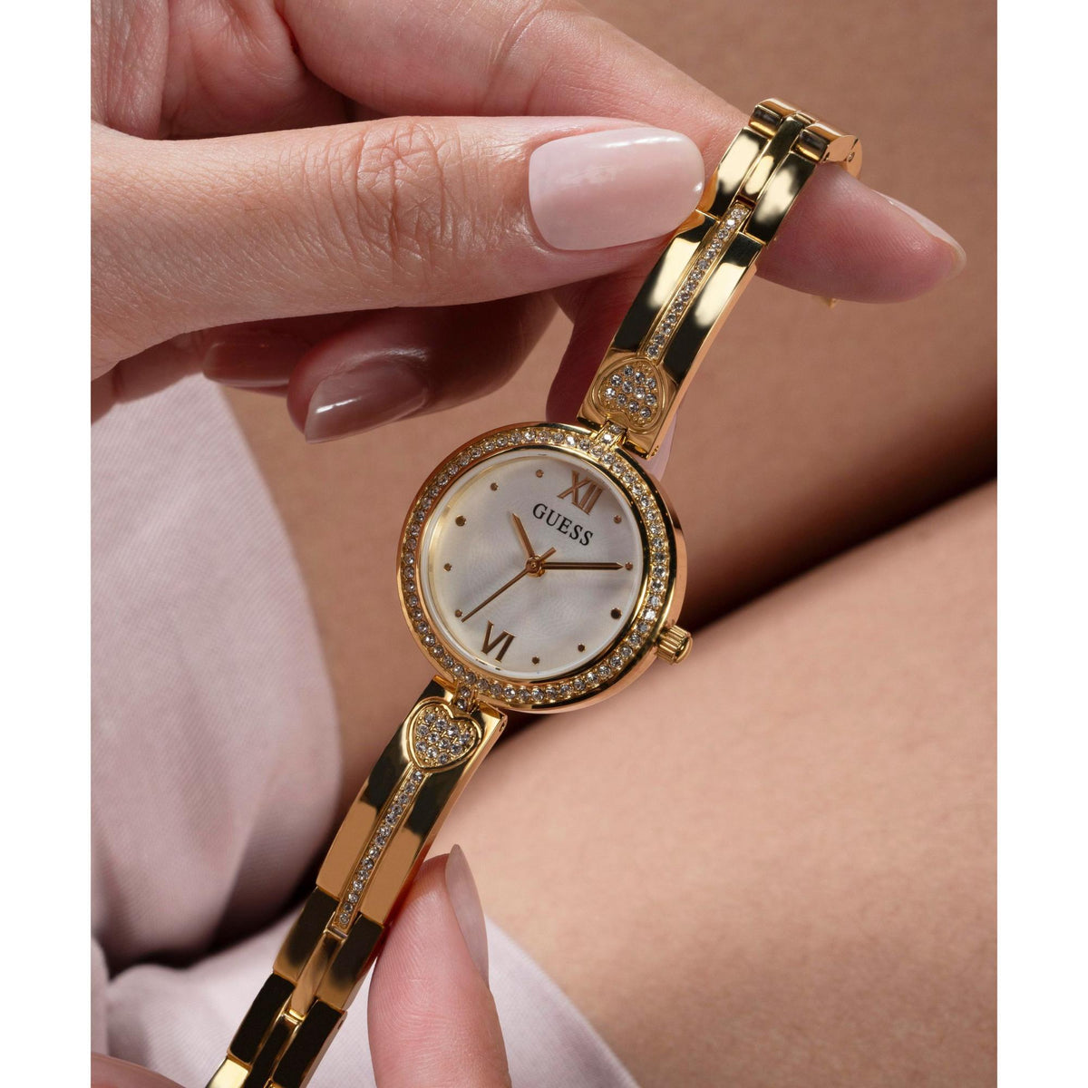 Ladies gold tone analog watch on wrist with white dial and crystal hour markers