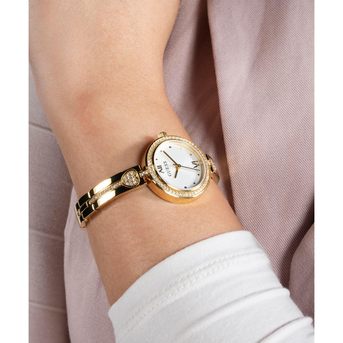 Ladies gold tone analog watch on wrist with white dial, Roman numerals, and crystals