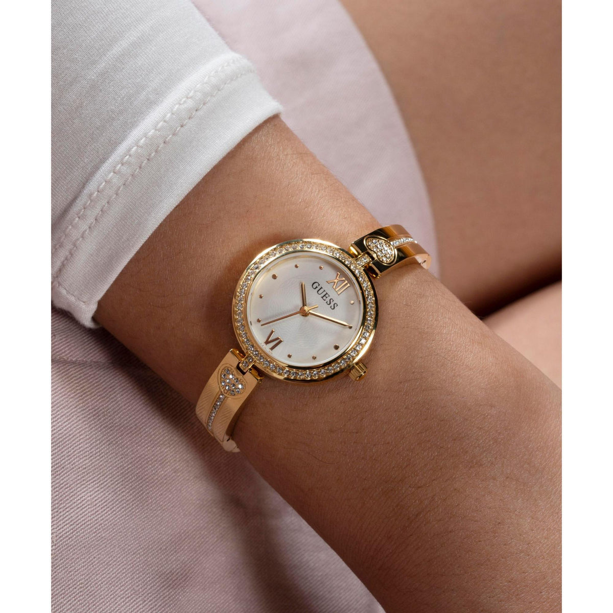 Ladies gold tone analog watch on wrist, white dial with crystal bezel and heart charm