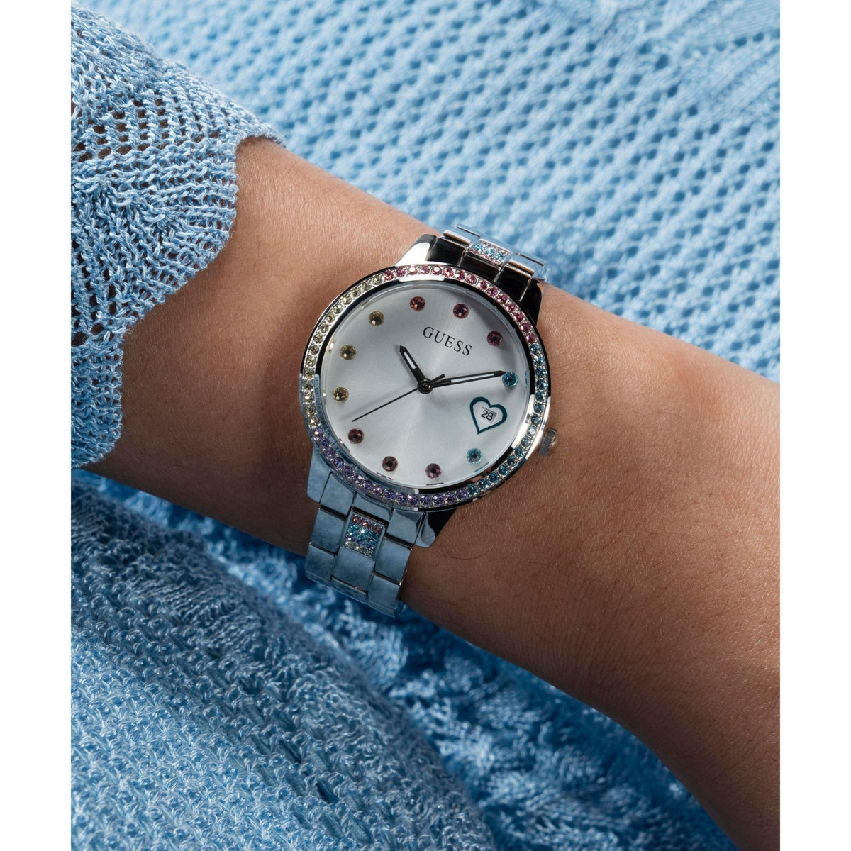 Ladies silver watch with crystal bezel, white heart dial, and steel bracelet on wrist