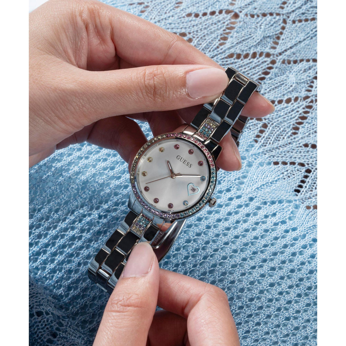 Ladies silver watch close-up with heart dial crystals and steel bracelet held in hands