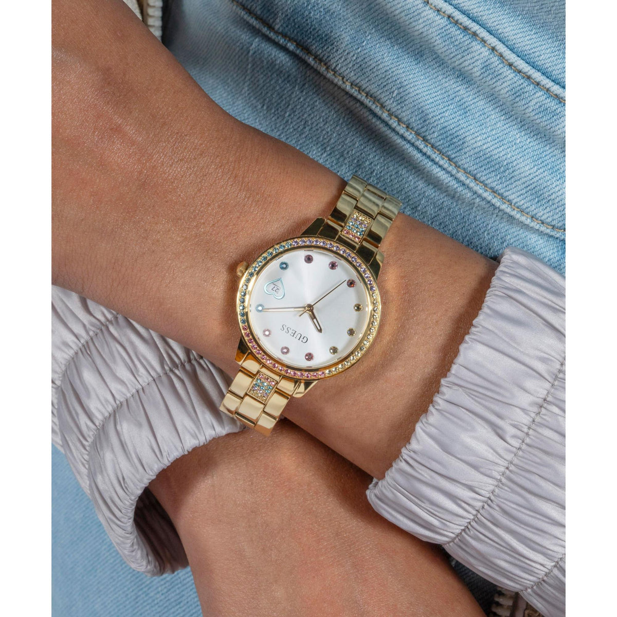 Gold tone ladies watch close-up on wrist with white dial, crystal links, and metal bracelet.