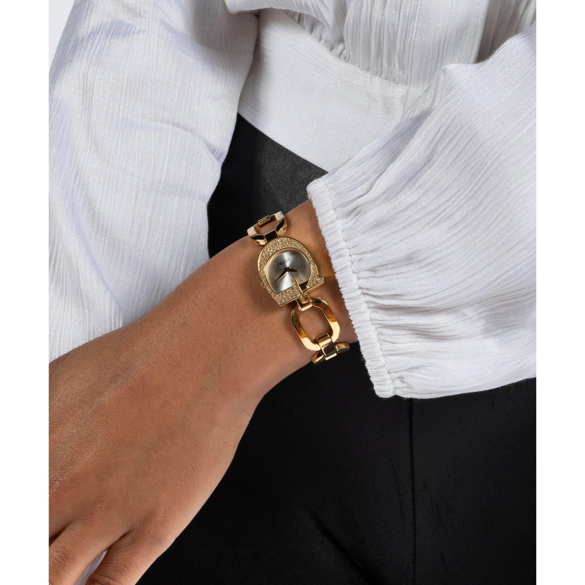 Gold tone analog ladies watch on wrist with silver dial and crystal bezel, polished link band