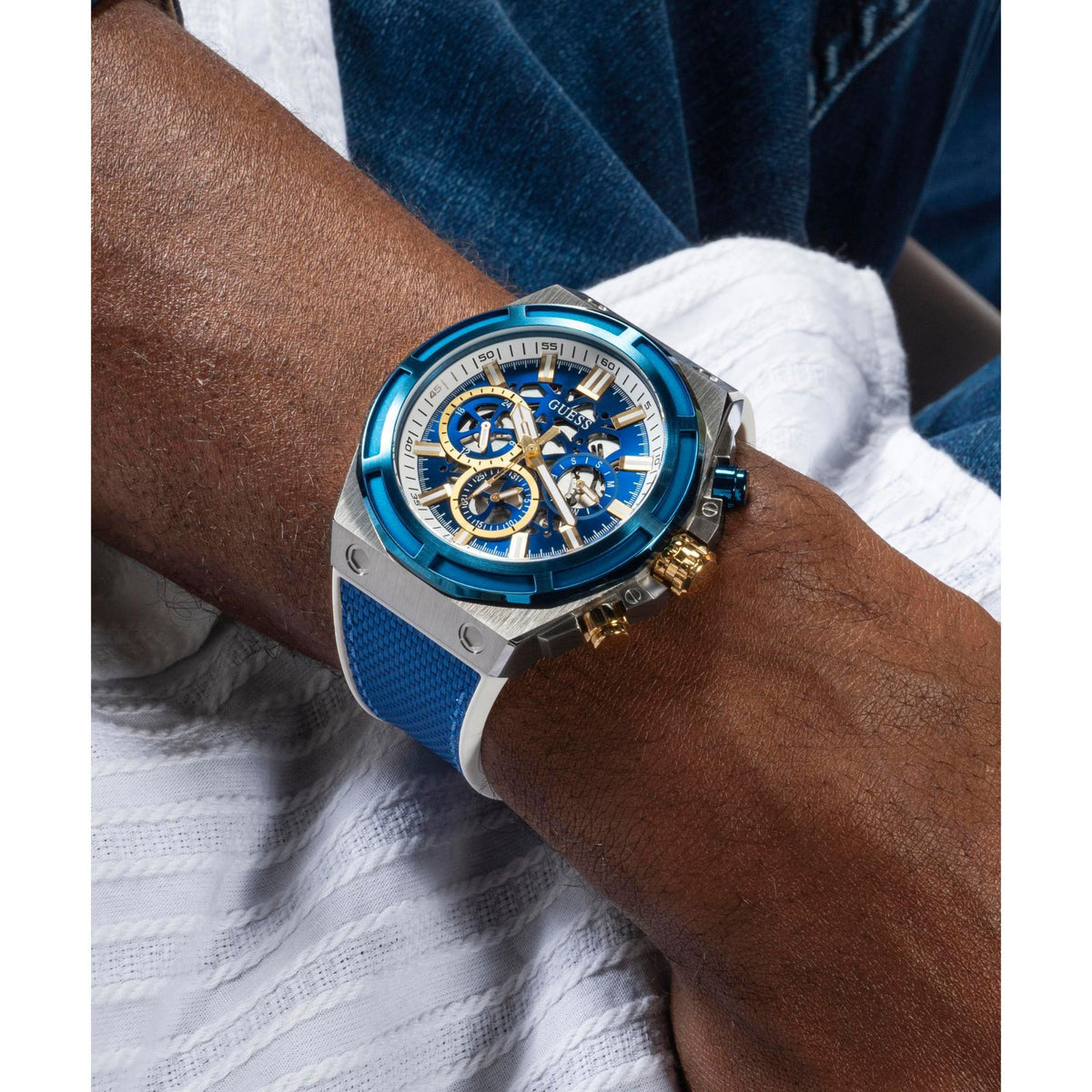 Men's chronograph wrist watch with blue dial and blue silicone strap on white shirt