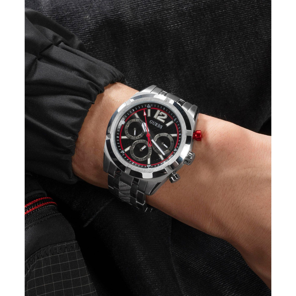 Men's silver steel wristwatch with black dial, red accents, and three subdials on wrist