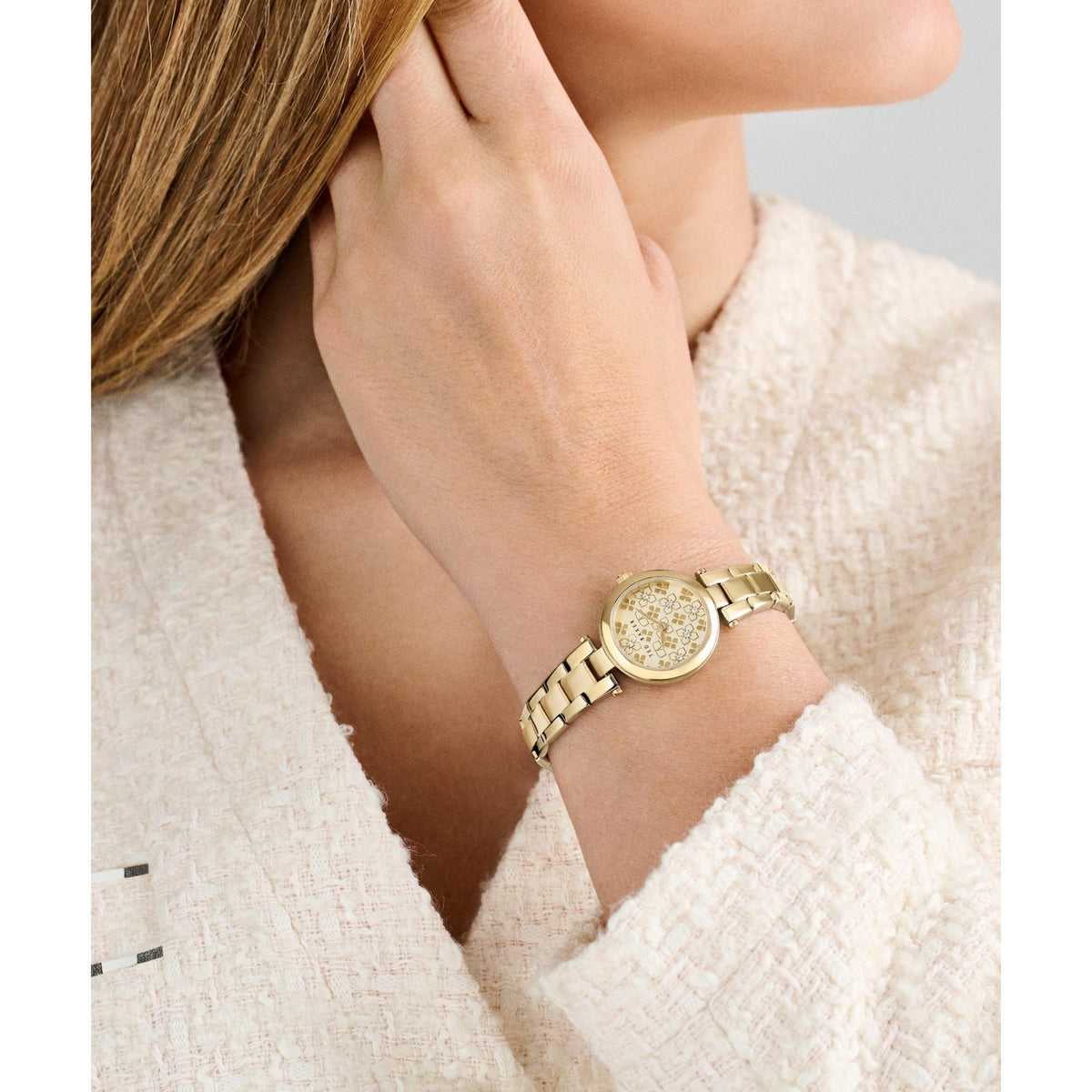Gold-tone ladies watch on wrist, round dial with floral pattern