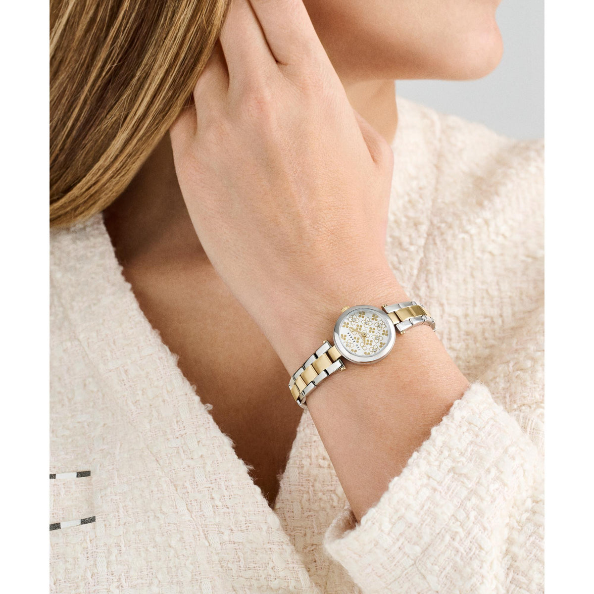 Two-tone ladies wristwatch worn on wrist, round silver dial and link bracelet