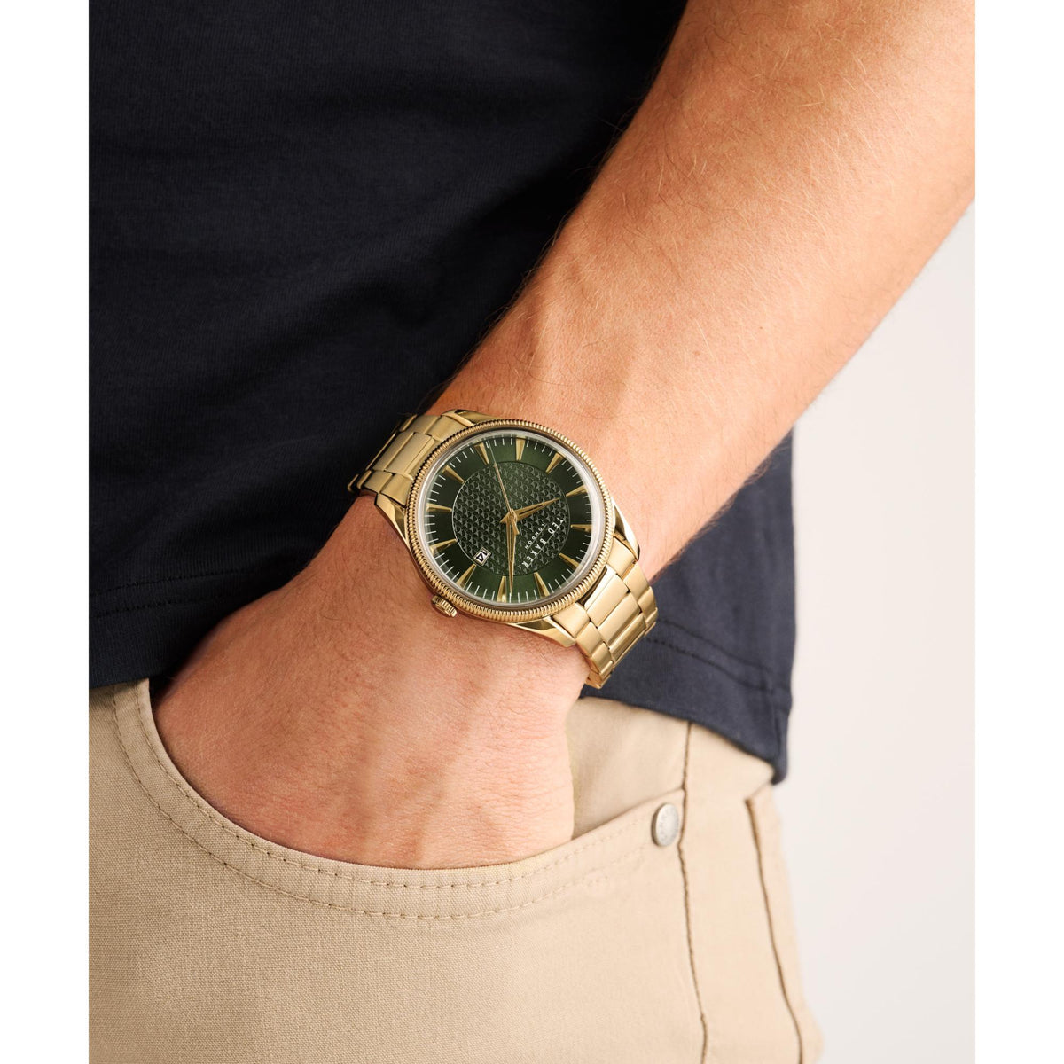 Men's gold-tone watch on wrist with green textured dial and date window