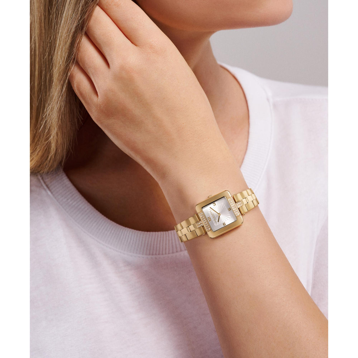 Women's gold-tone watch on wrist, square white dial with linked bracelet