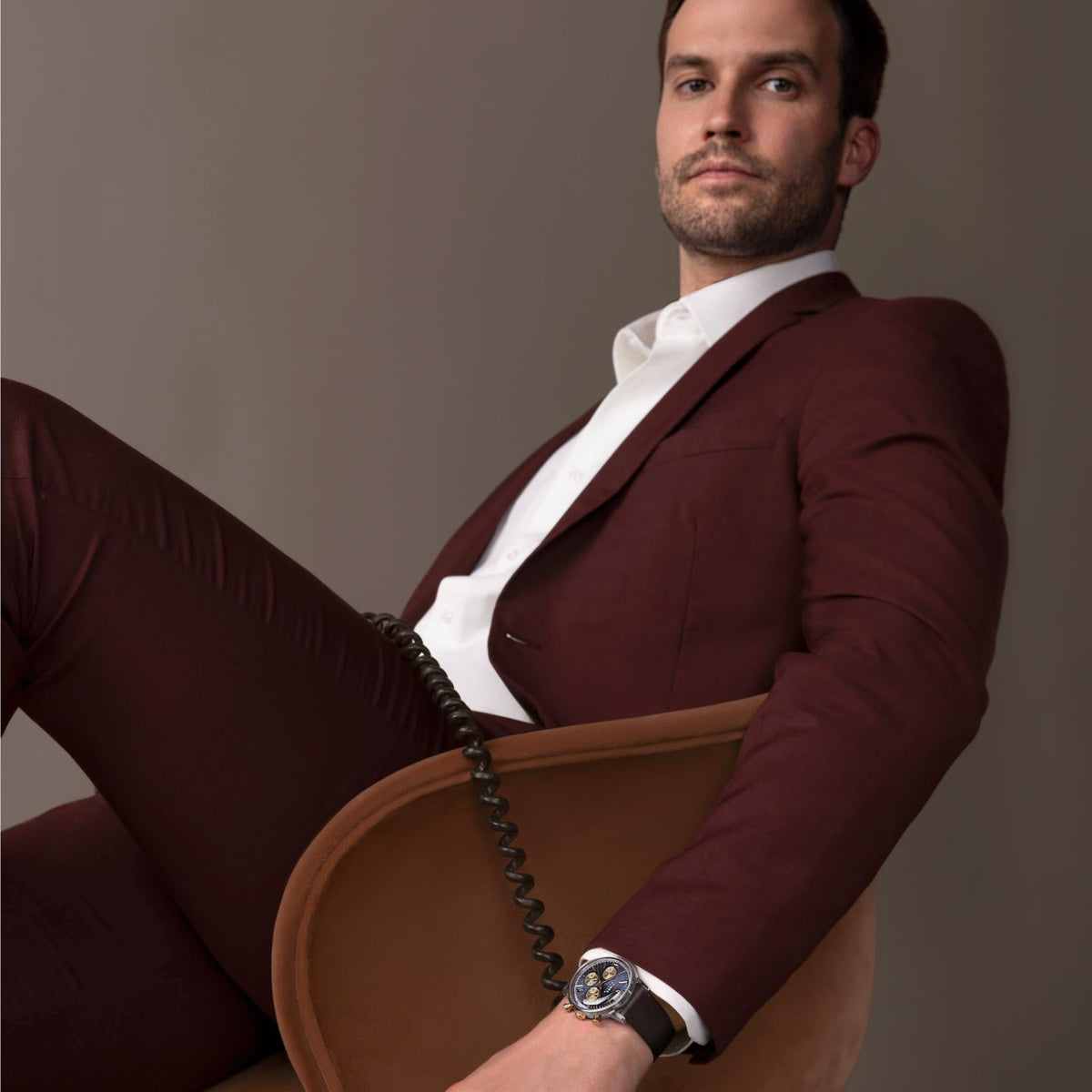 Timex chronograph watch on man's wrist with brown leather strap and navy dial