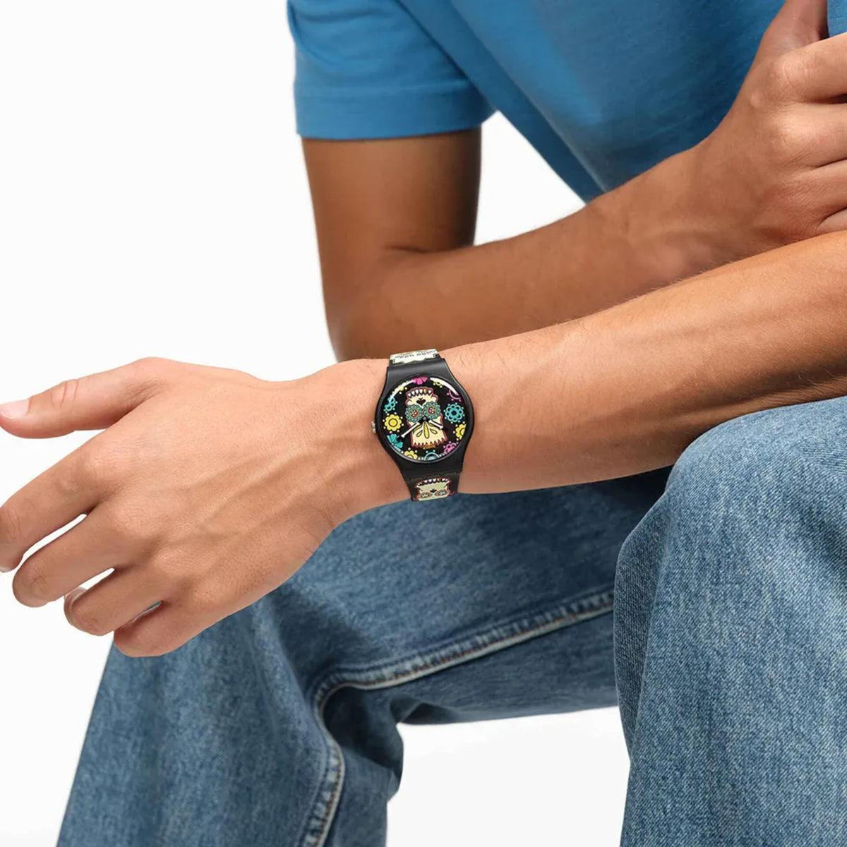 Swatch skull dial quartz watch on denim-clad wrist with black printed strap