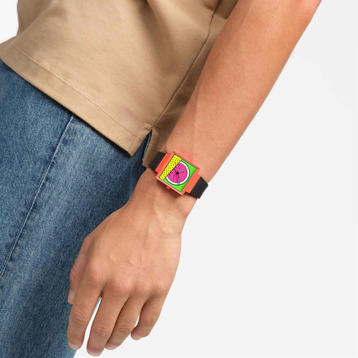 Swatch watch on wrist with pink dial and black strap worn with blue jeans