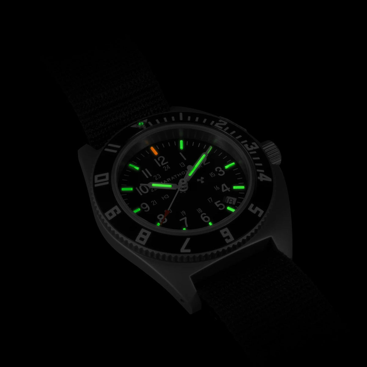 Men's steel watch with glowing green luminous dial and black fabric strap in dark