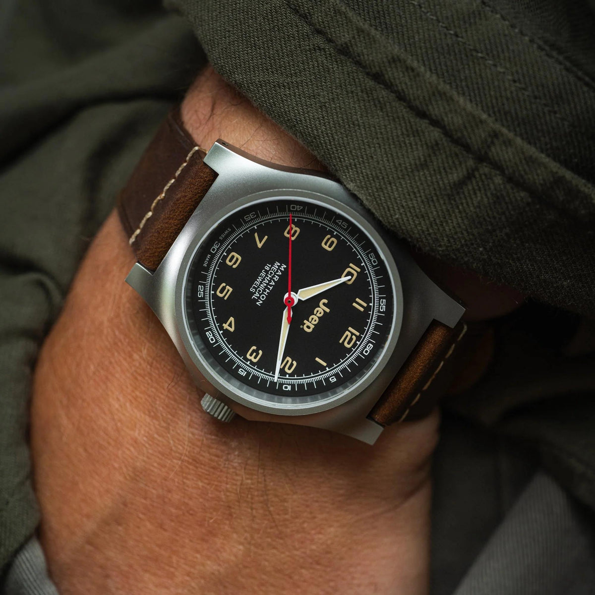 Men's mechanical watch on wrist with black dial and brown leather strap, red seconds hand