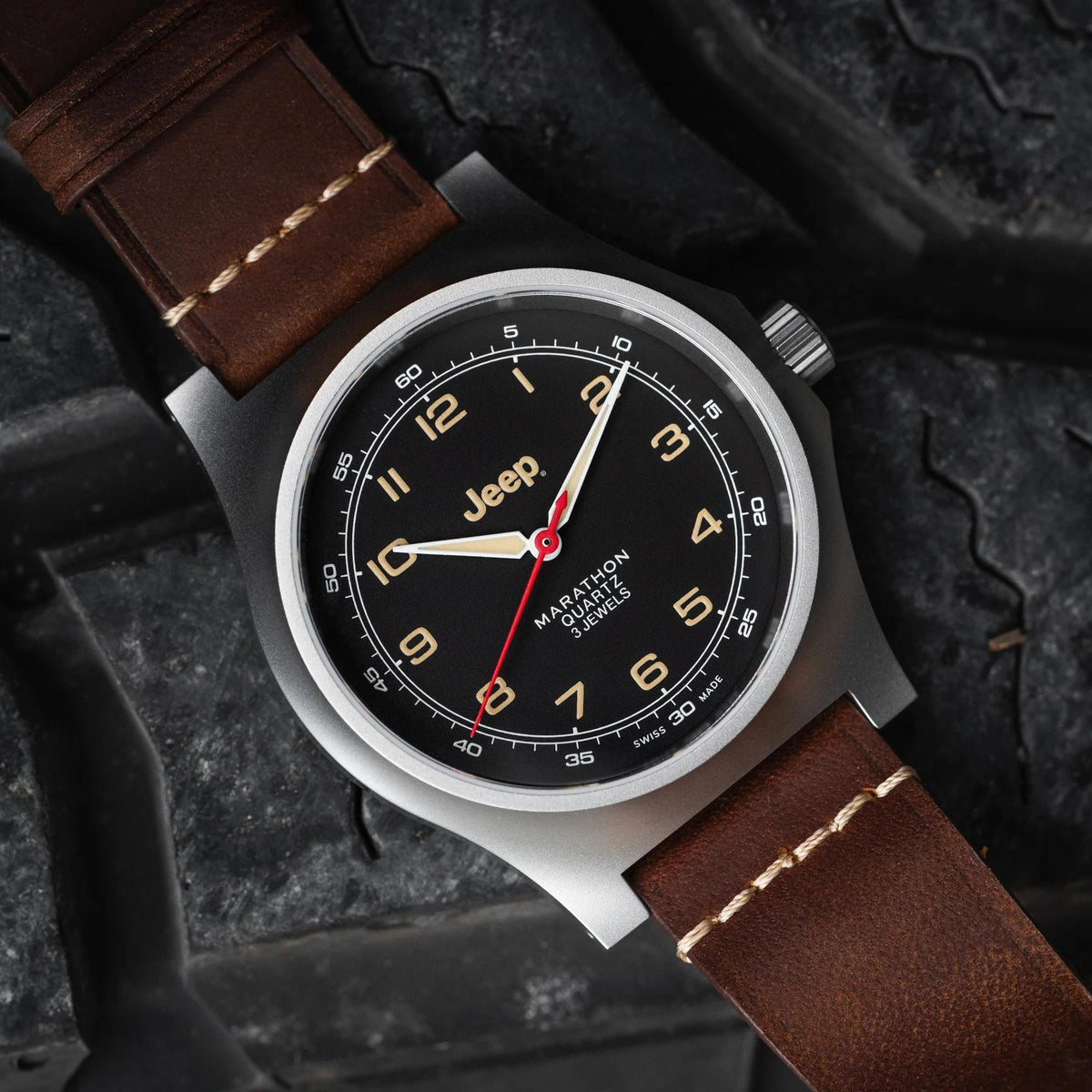 Men's quartz wristwatch on textured background; black dial with red seconds hand, brown strap.
