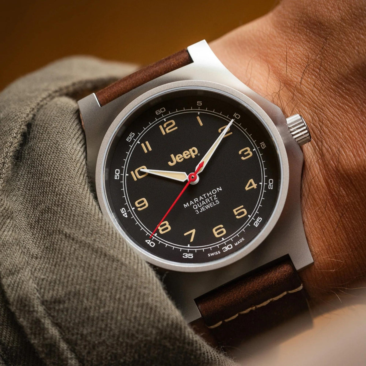 Men's wristwatch worn on wrist; black dial, stainless steel case, brown leather strap.