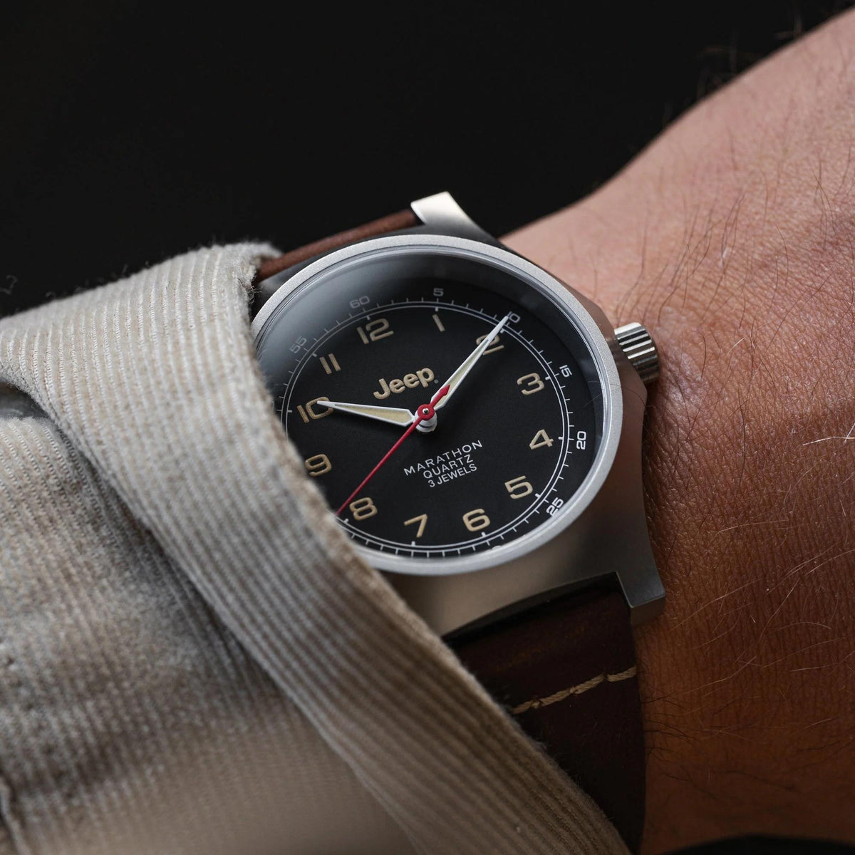 Men's quartz wristwatch on wrist with black dial and brown leather strap, silver case.