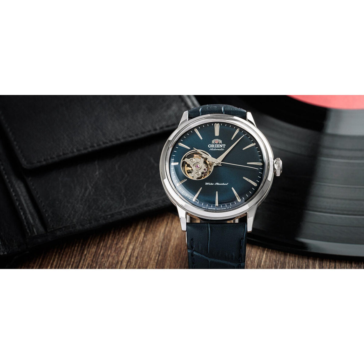 Men's automatic watch front view with blue dial, open-heart feature, silver case and dark blue strap
