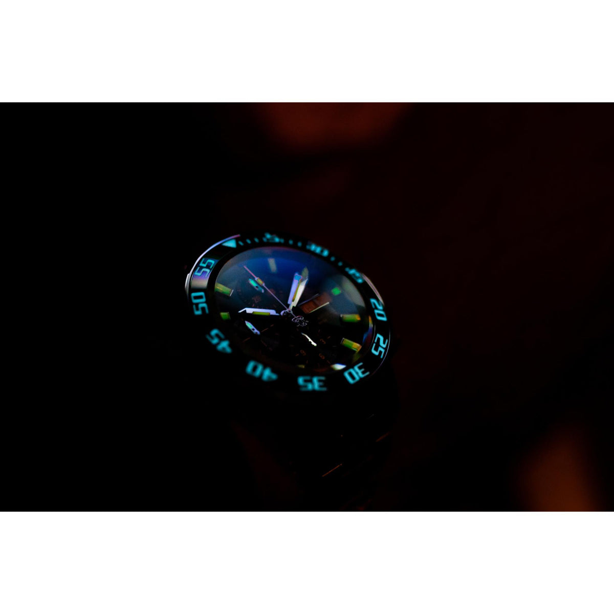 Men's diver watch close-up with black dial and blue-green glowing bezel markers