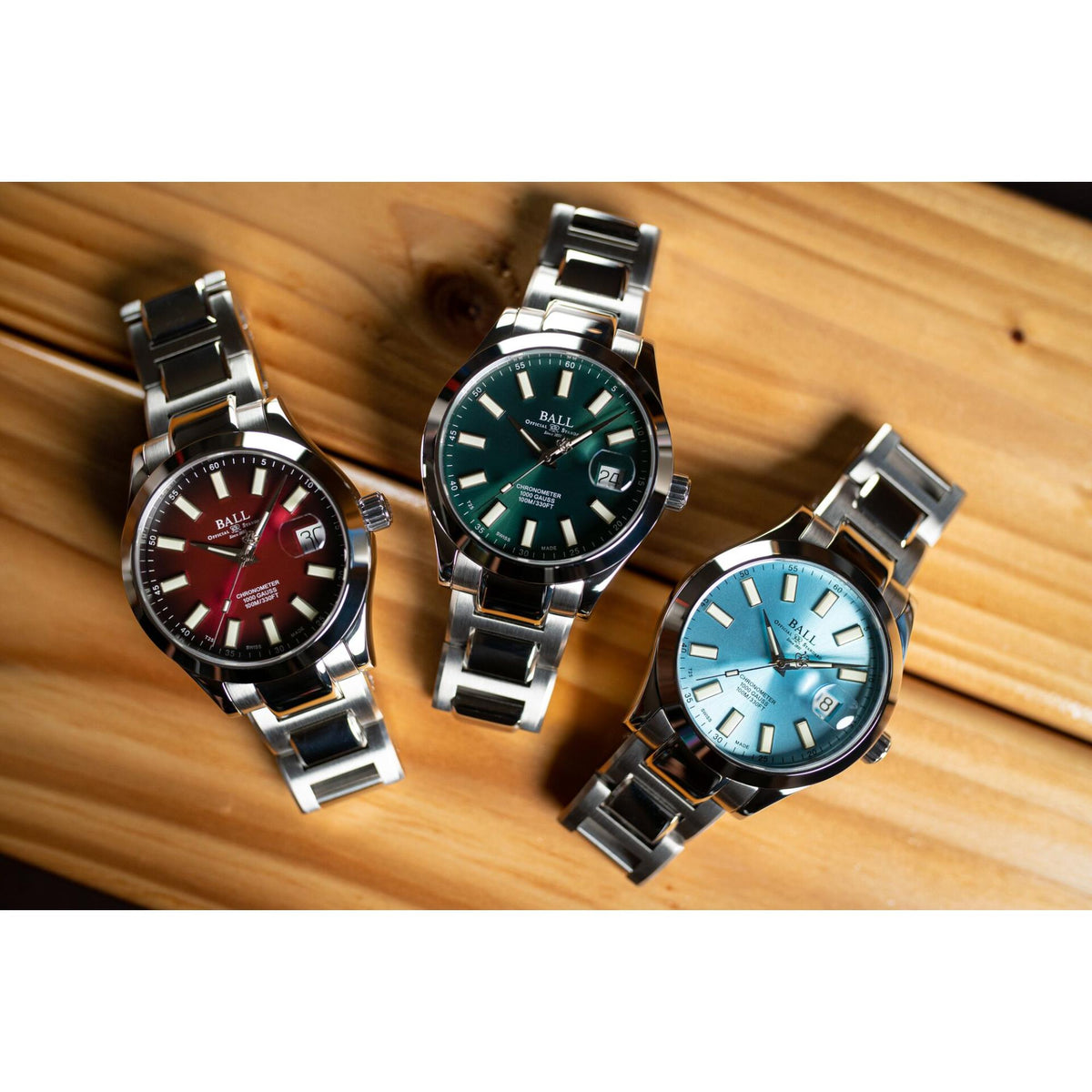 Set of three metal bracelet watches with red, green, and light blue dials