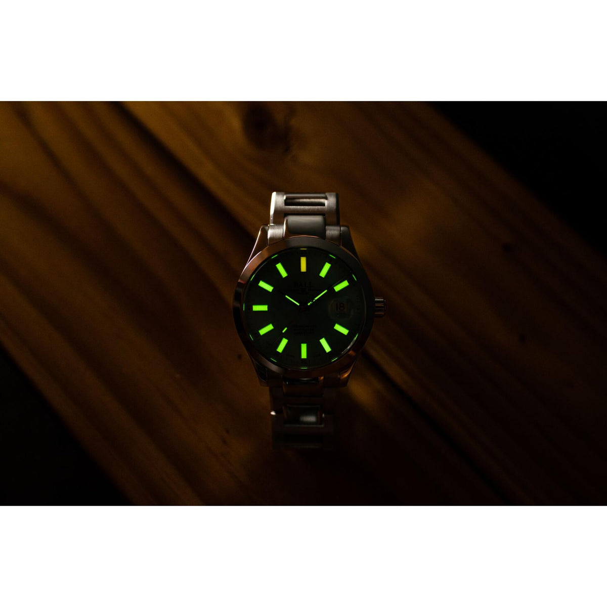 Black sport watch with green luminous dial markers and metal bracelet